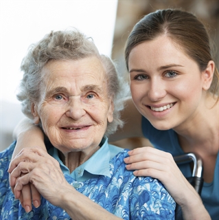 Senior aged woman smiling next to a young woman who is a nurse