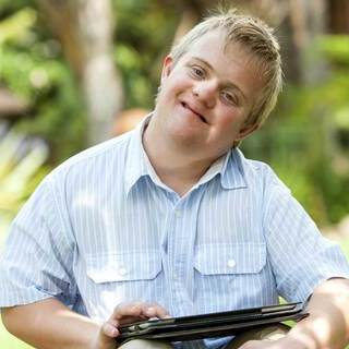 Younger man with down syndrome using a tablet