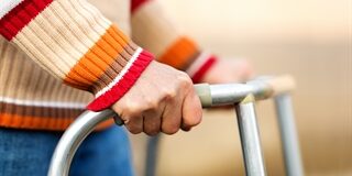 An image of a person's waist with their hands holding a walker support device.