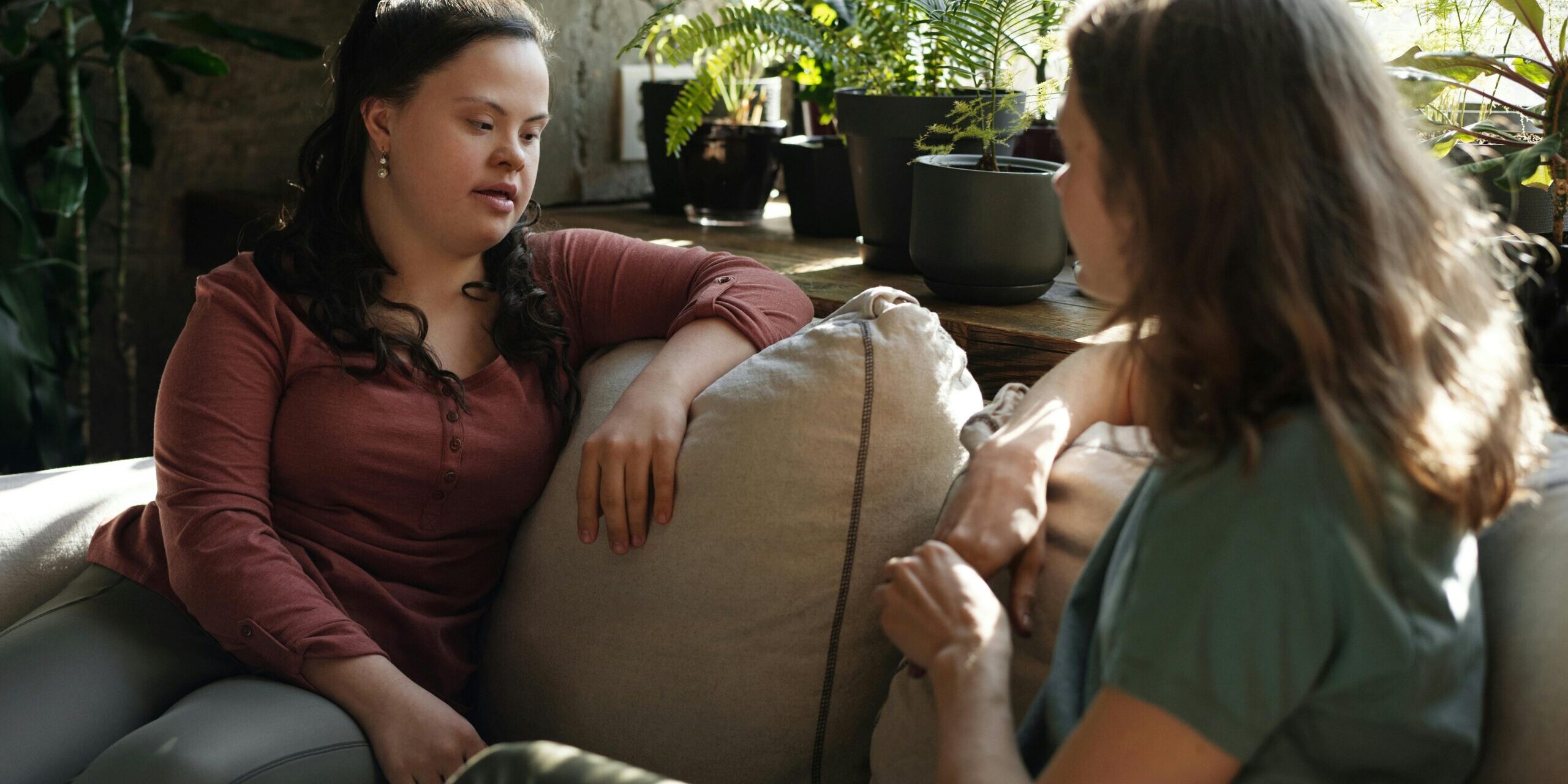 A woman with Down Syndrome speaks to a therapist across from her on a couch